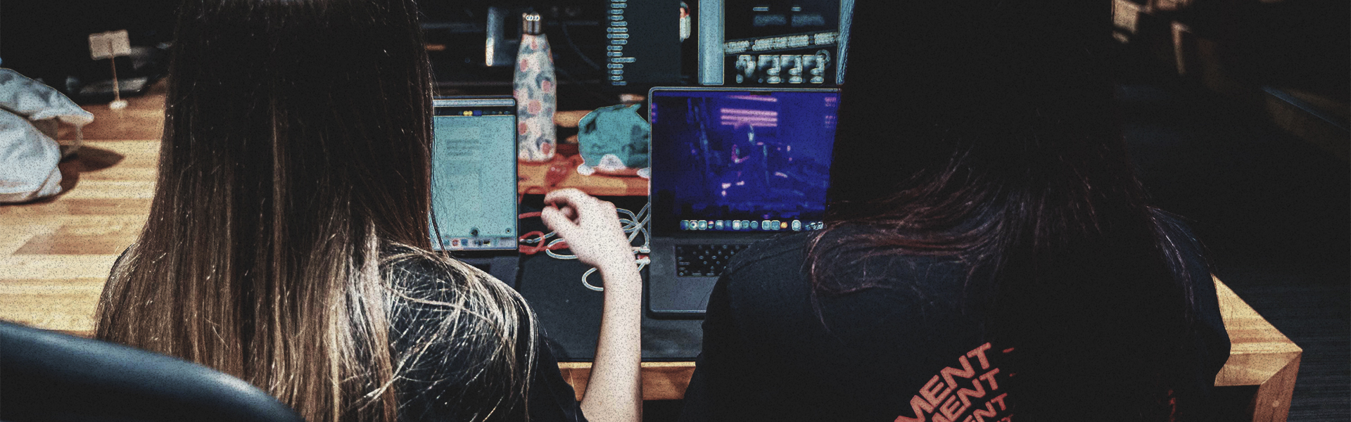 the backs of two people sitting at their computers