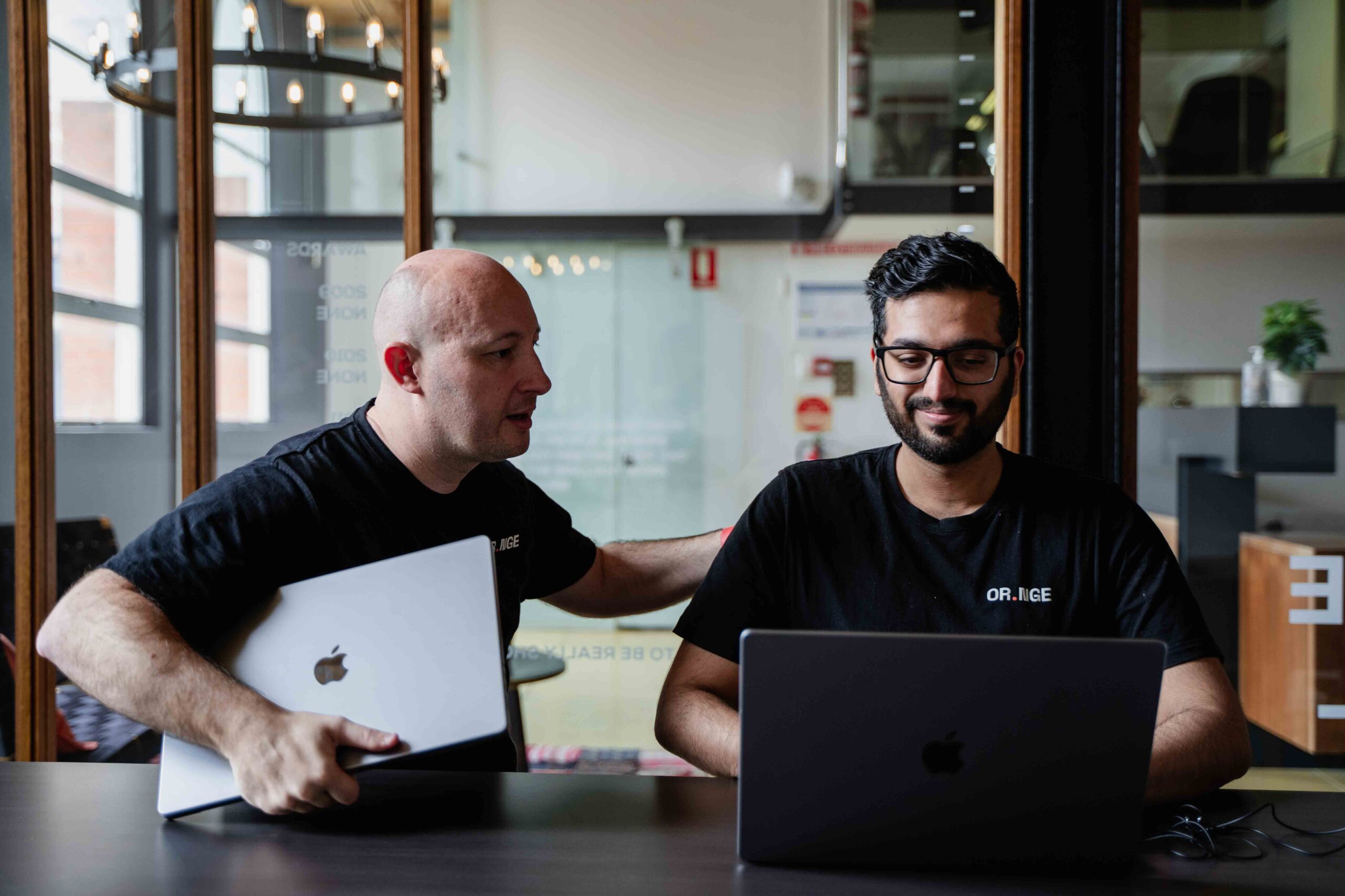 Two men working on laptops in office.