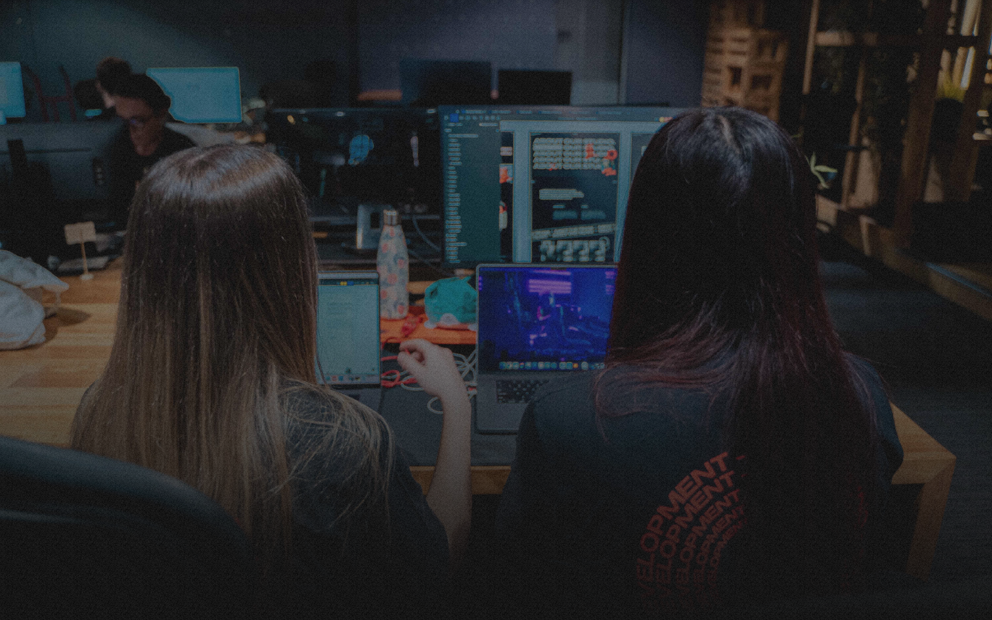 Two people working on laptops in a dark room.