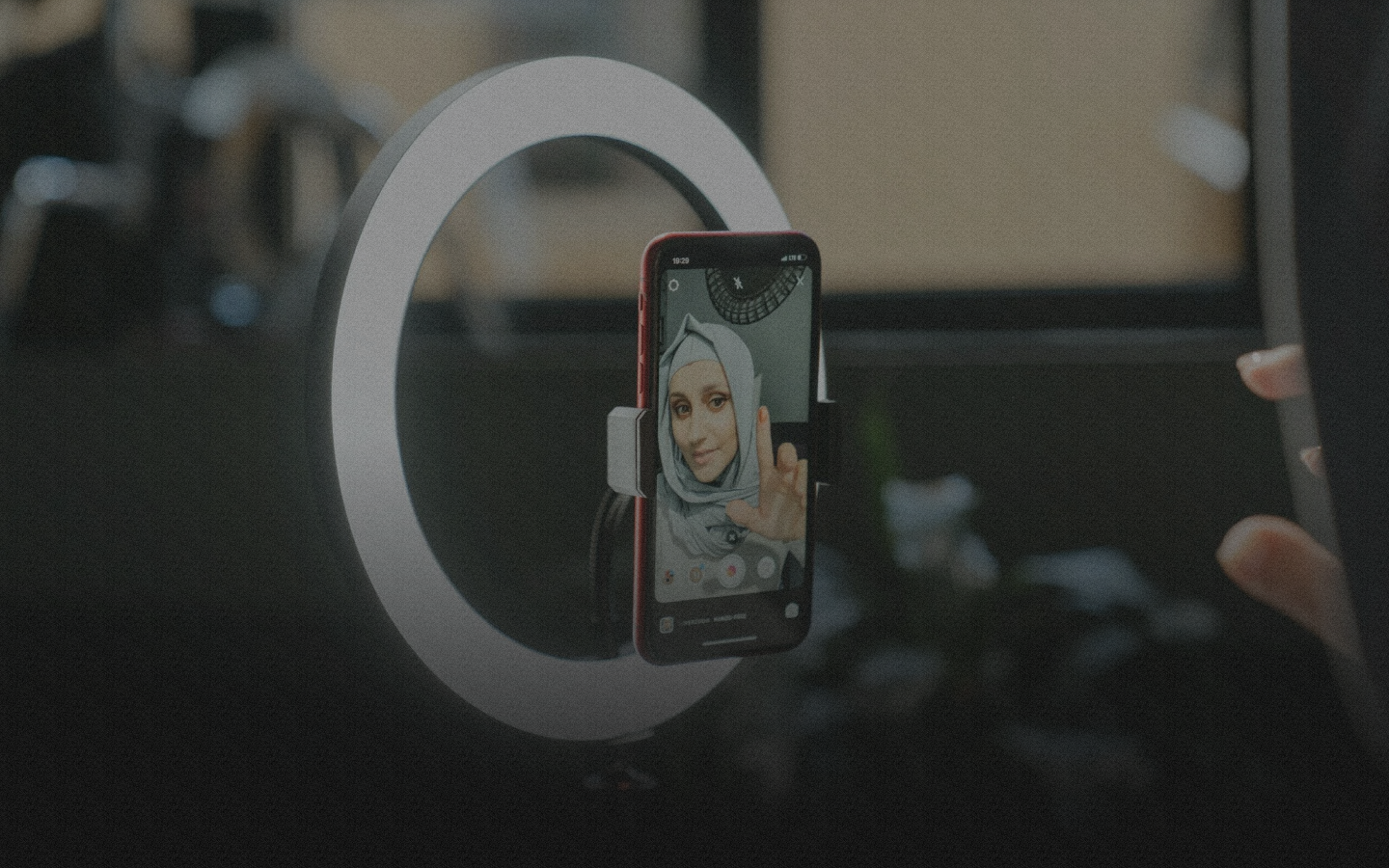 Woman filming with ring light and phone.