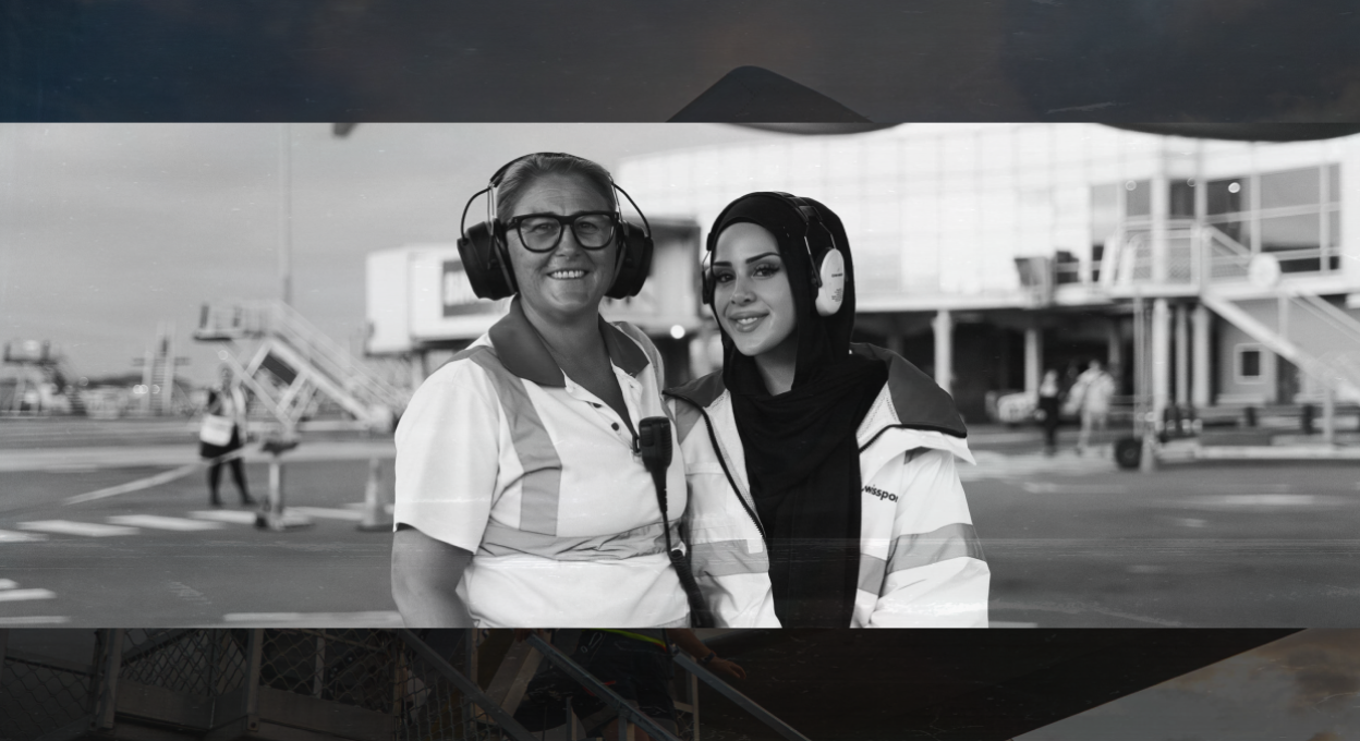 Two women in airport uniforms smiling.